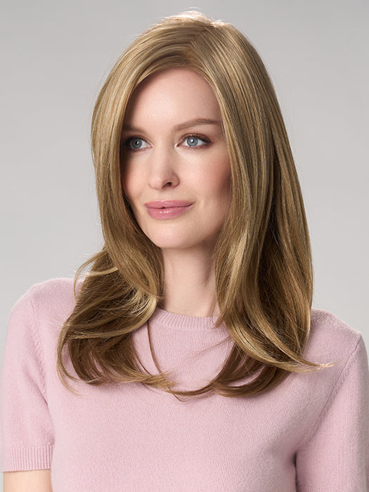 Woman with long blonde hair wearing a pink sweater on a gray background