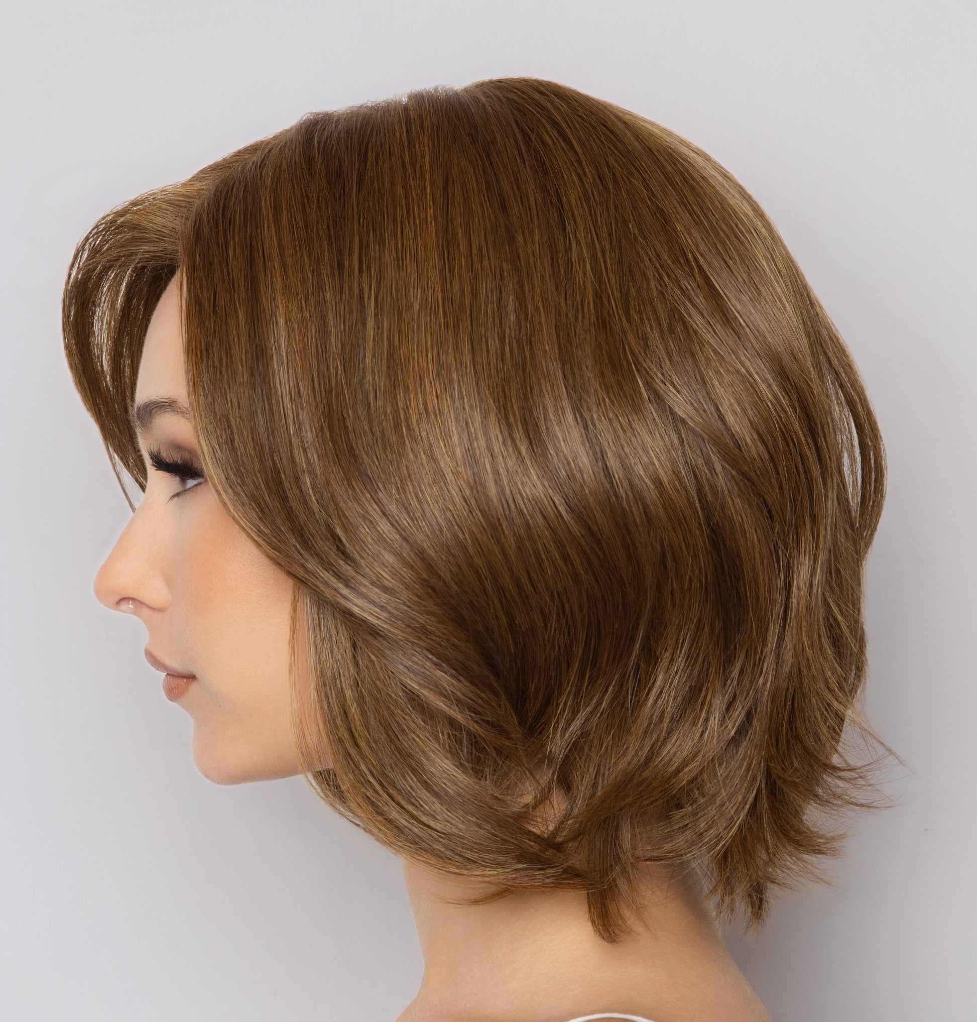 Brown wig on a mannequin head against a light gray background