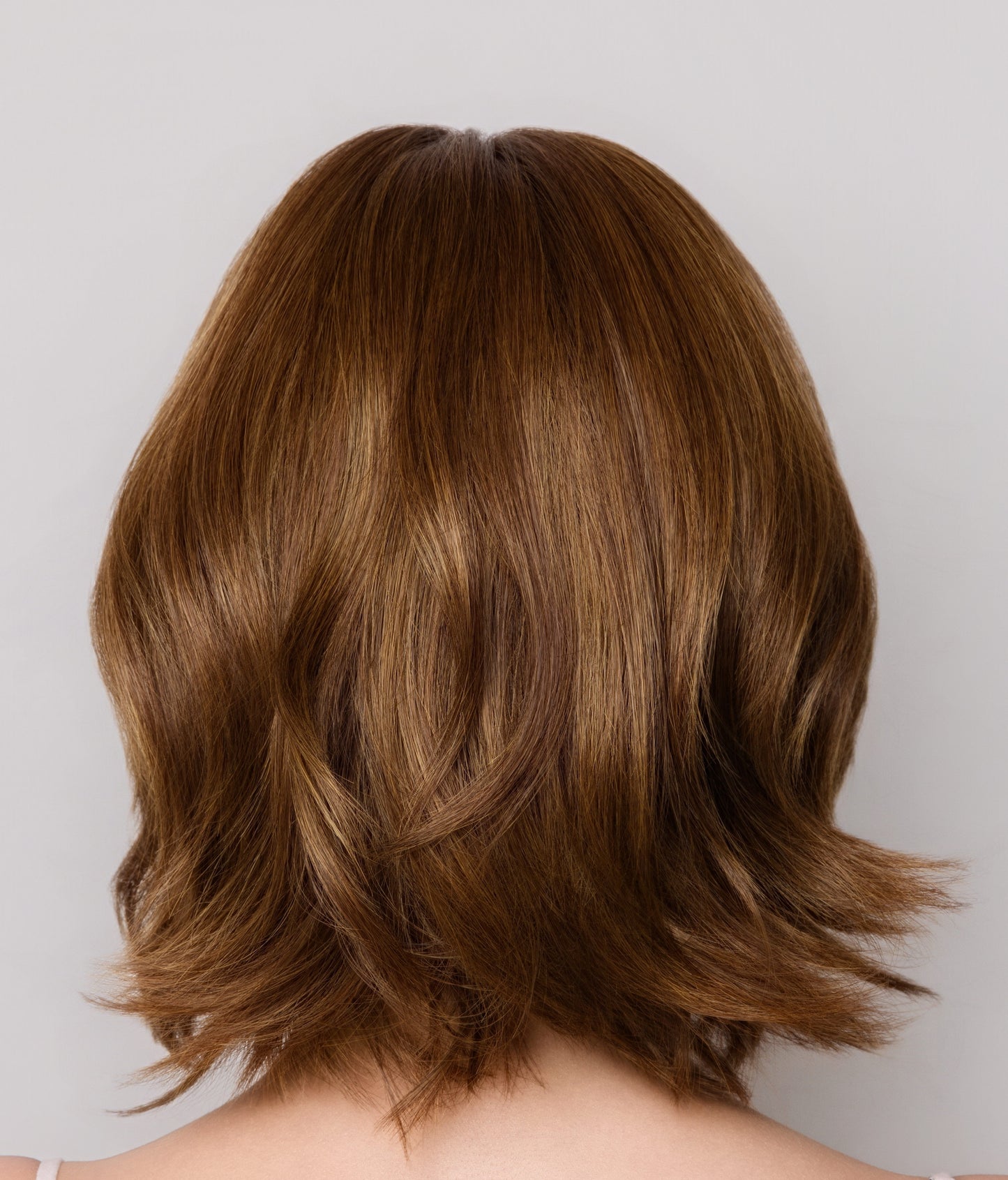 Back view of a person with shoulder-length brown hair on a plain background