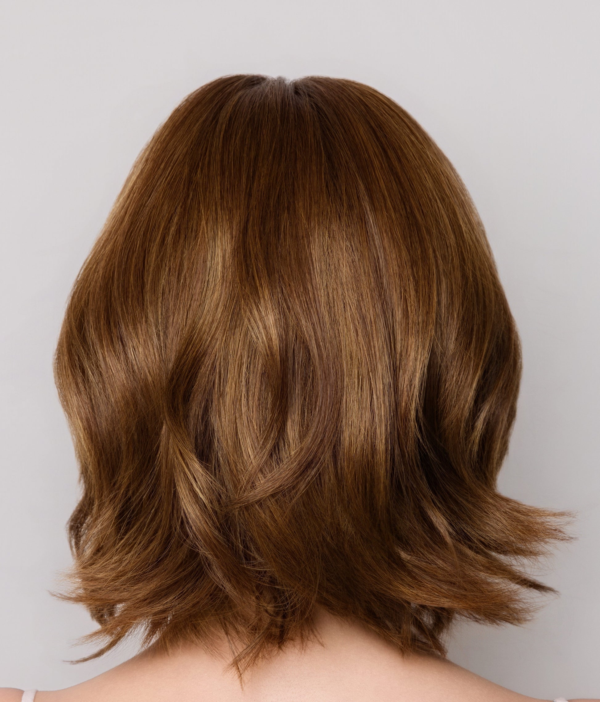 Back view of a person with shoulder-length brown hair on a plain background