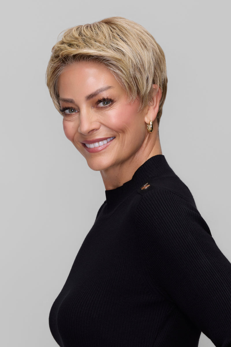 Woman with short blonde hair wearing a black sweater against a gray background