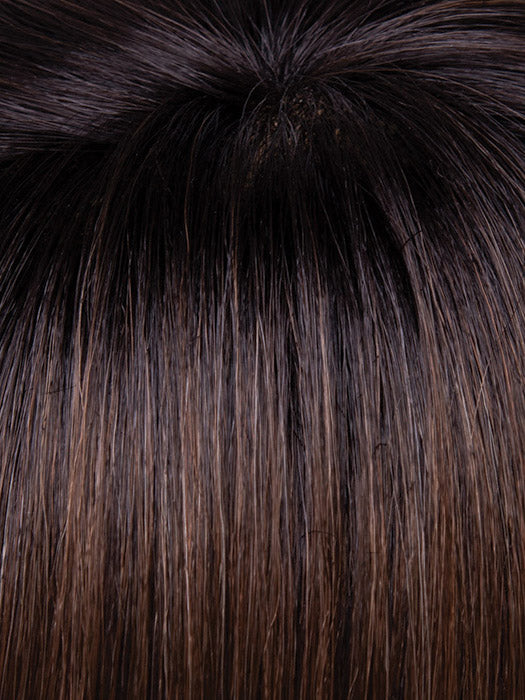Close-up of dark brown hair with a fluffy black pom-pom on top.