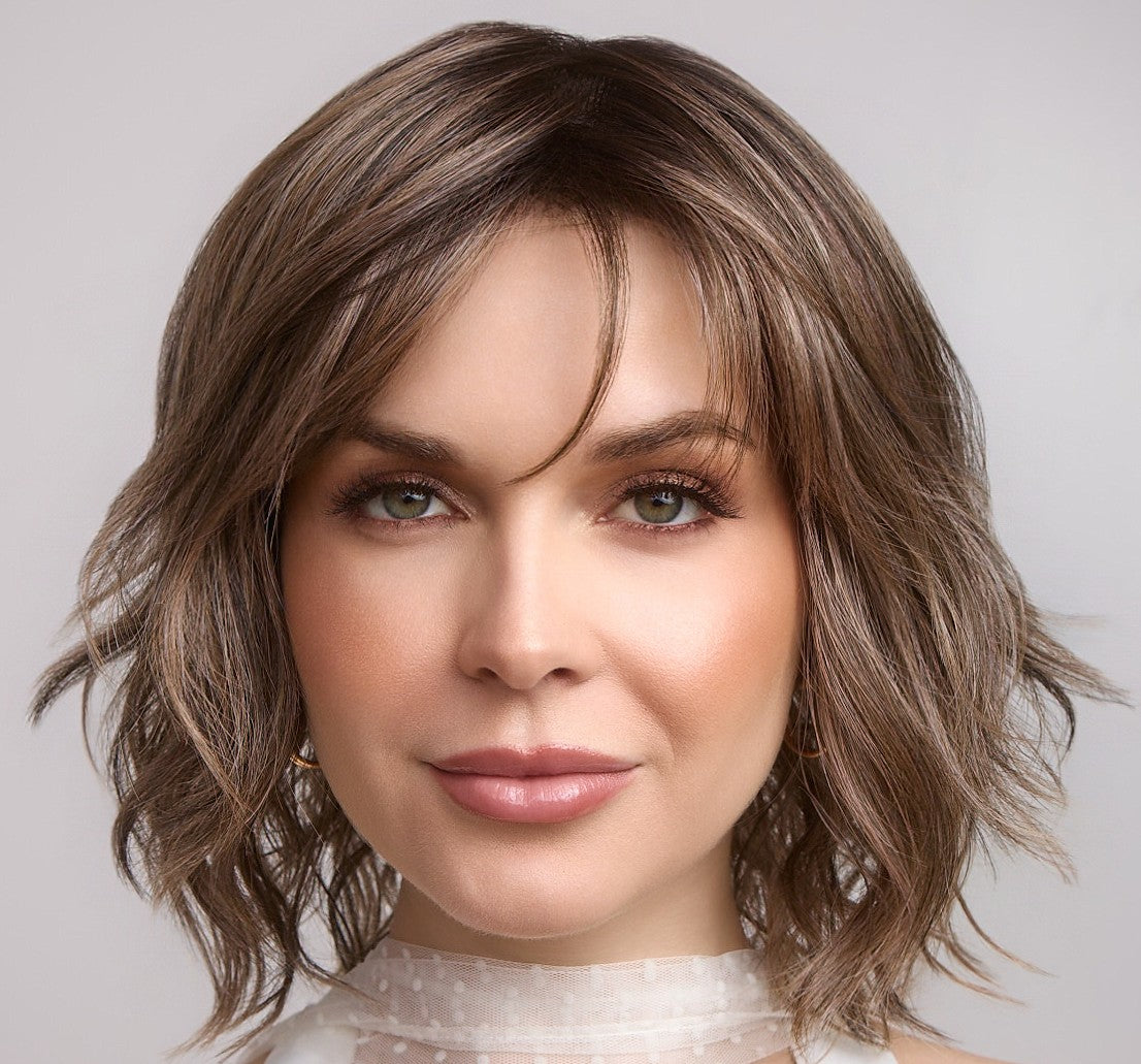 Woman with styled brown hair against a neutral background
