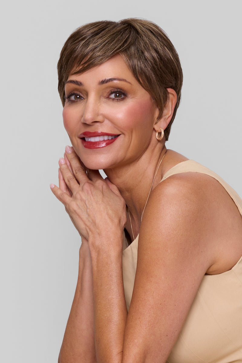 Woman with short brown hair and red lipstick posing against a plain background