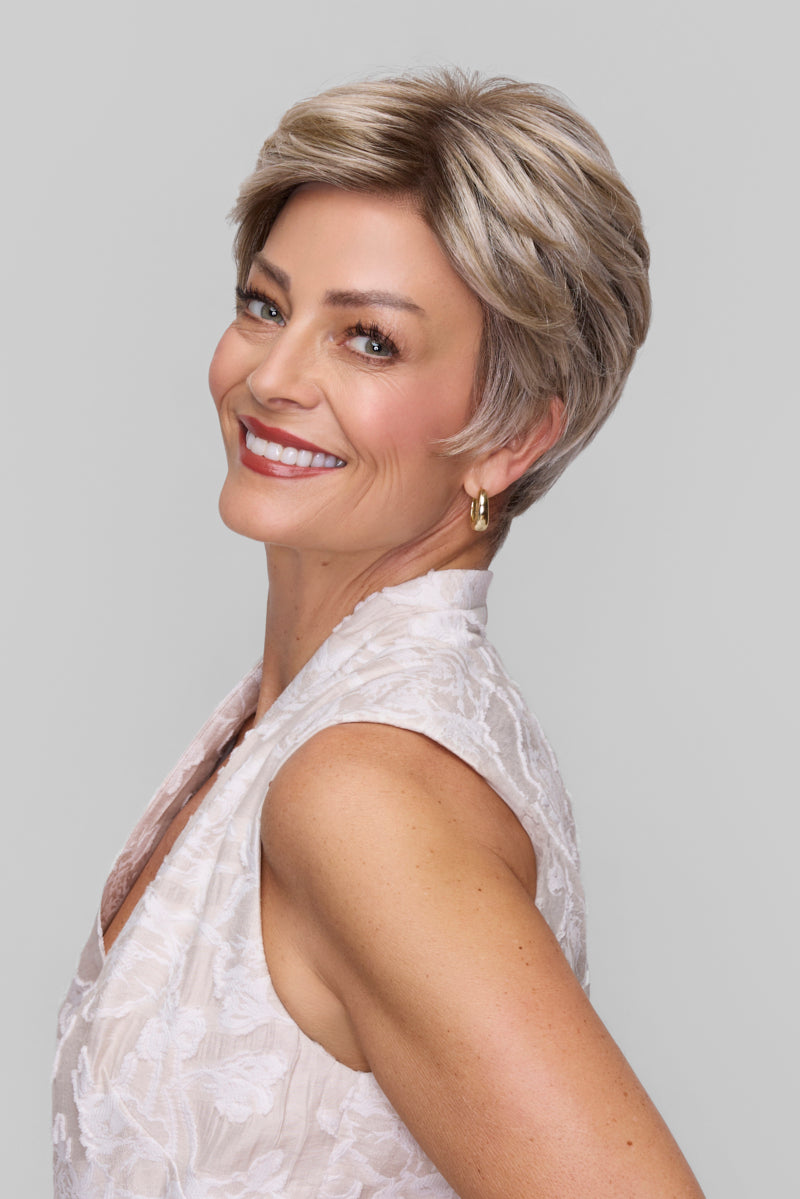 Woman with short, styled hair wearing a white sleeveless top against a plain background