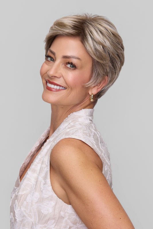 Woman with short, styled hair wearing a white sleeveless top against a plain background