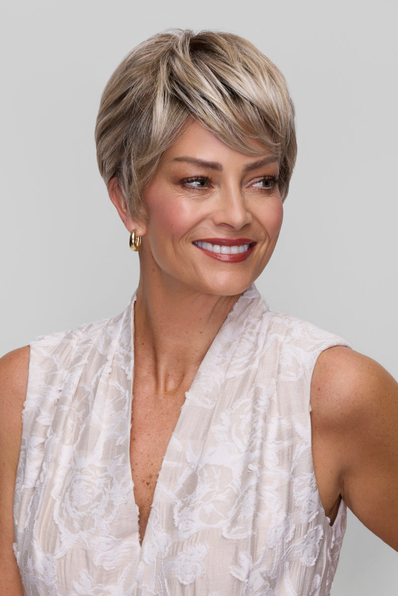 Woman with short, styled hair wearing a white sleeveless top against a plain background