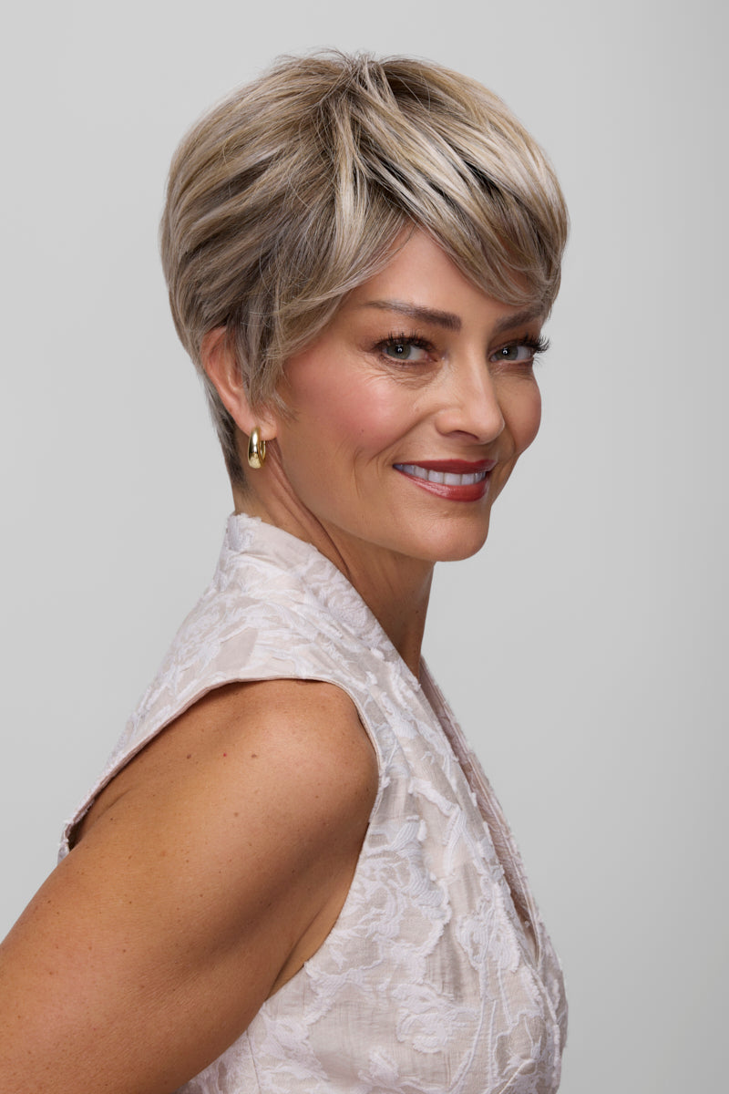 Woman with styled short hair wearing a light-colored top against a plain background